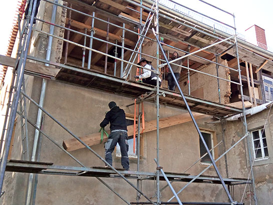 Nachdem die zerstörten Bauteile entfernt wurden, können die ersten neuen Hölzer mit dem Kettenzug nach oben gebracht werden